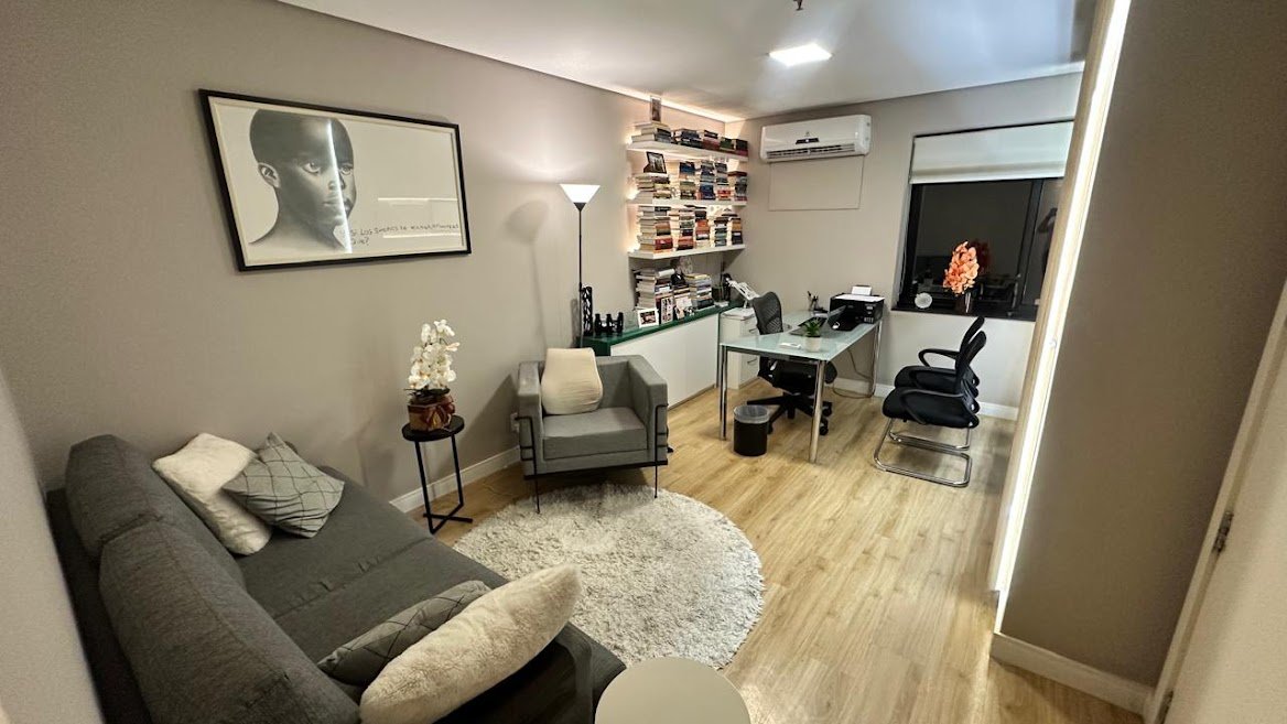 Sala de atendimento com sofá, poltrona e mesa na Clínica Íntegra